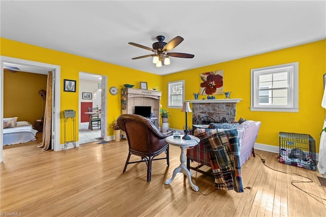 sitting room with a healthy amount of sunlight, a fireplace, baseboards, and hardwood / wood-style flooring