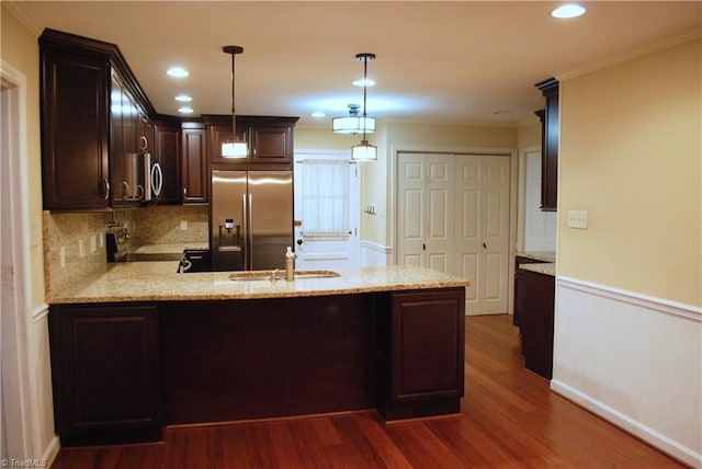 kitchen with kitchen peninsula, sink, ornamental molding, appliances with stainless steel finishes, and pendant lighting