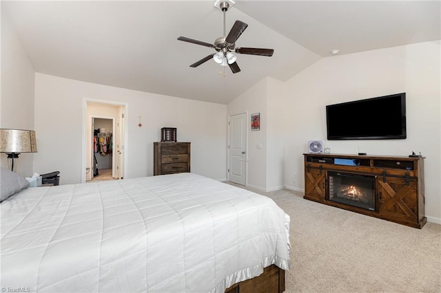 bedroom featuring baseboards, lofted ceiling, ceiling fan, a glass covered fireplace, and carpet flooring