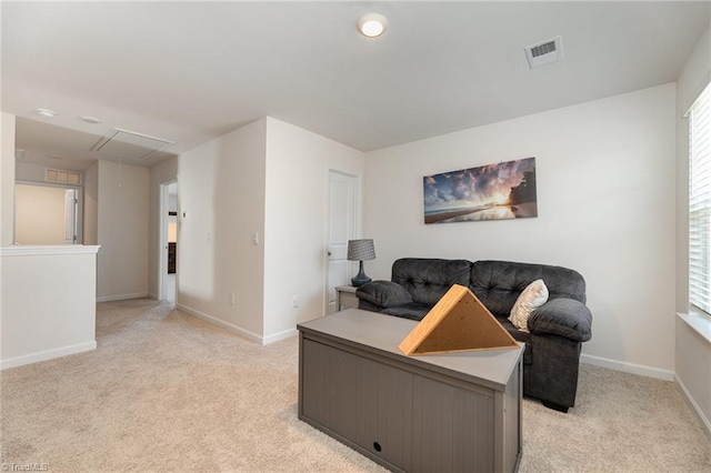 living area featuring attic access, visible vents, and light carpet