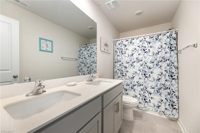 bathroom featuring a sink, visible vents, toilet, and double vanity