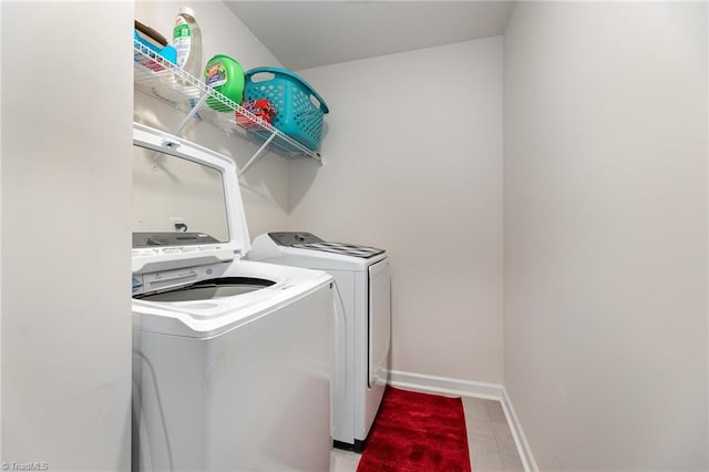 clothes washing area featuring laundry area, separate washer and dryer, and baseboards