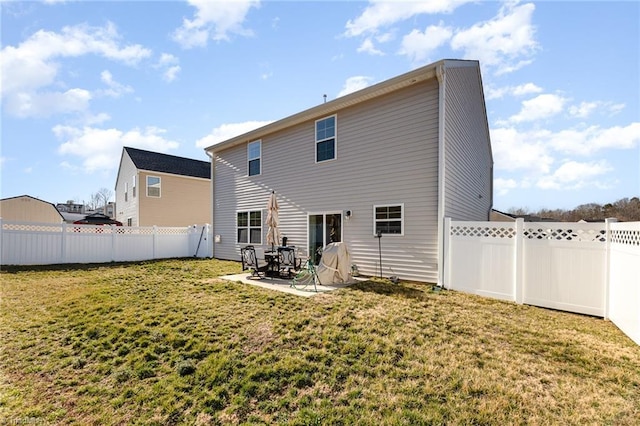 rear view of property featuring a yard, a patio, and a fenced backyard