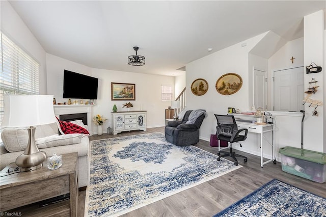 living room featuring stairway, a fireplace, baseboards, and wood finished floors