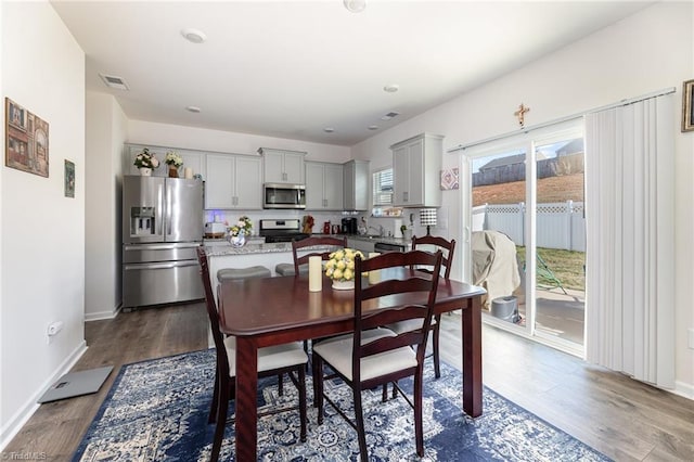 dining space with visible vents, baseboards, and dark wood finished floors