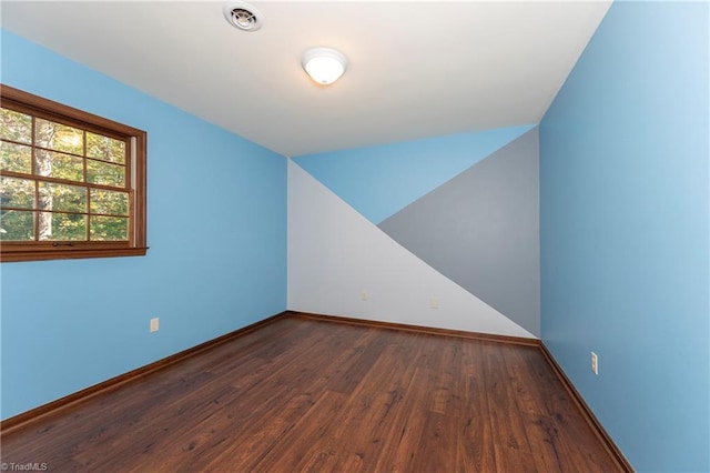 empty room featuring vaulted ceiling and dark hardwood / wood-style flooring