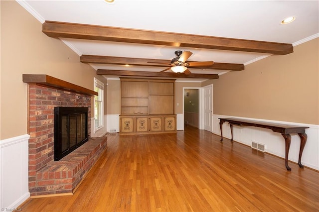 unfurnished living room featuring crown molding, a fireplace, beamed ceiling, and light wood-type flooring