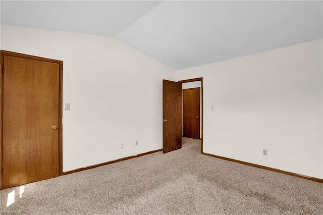 carpeted empty room with vaulted ceiling