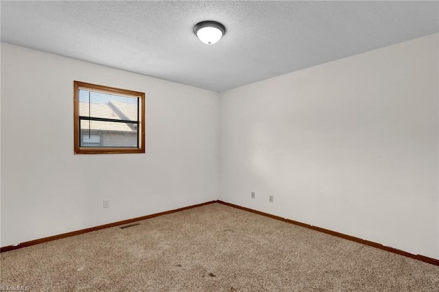 carpeted empty room featuring a textured ceiling