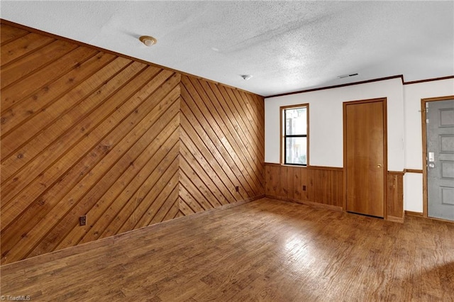 unfurnished bedroom featuring hardwood / wood-style floors, wood walls, and a textured ceiling