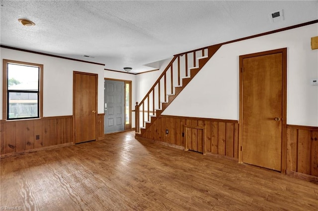 entryway featuring hardwood / wood-style floors, wooden walls, and a textured ceiling