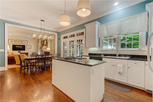 3612 Camden Falls Cir, Greensboro, NC 27410 - kitchen featuring dark countertops, stainless steel gas stovetop, white cabinets, a center island, and hanging light fixtures