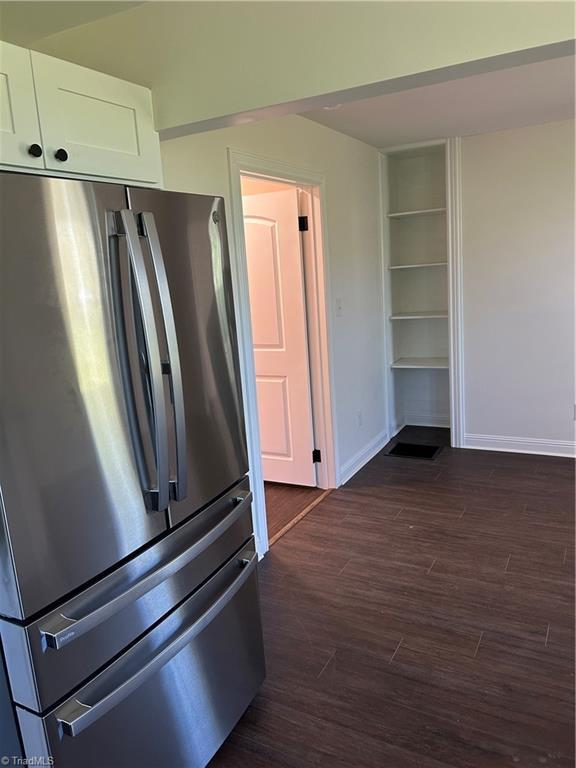 219 Highland Ave, Elkin, NC 28621 - kitchen with freestanding refrigerator, white cabinets, baseboards, and dark wood-style flooring