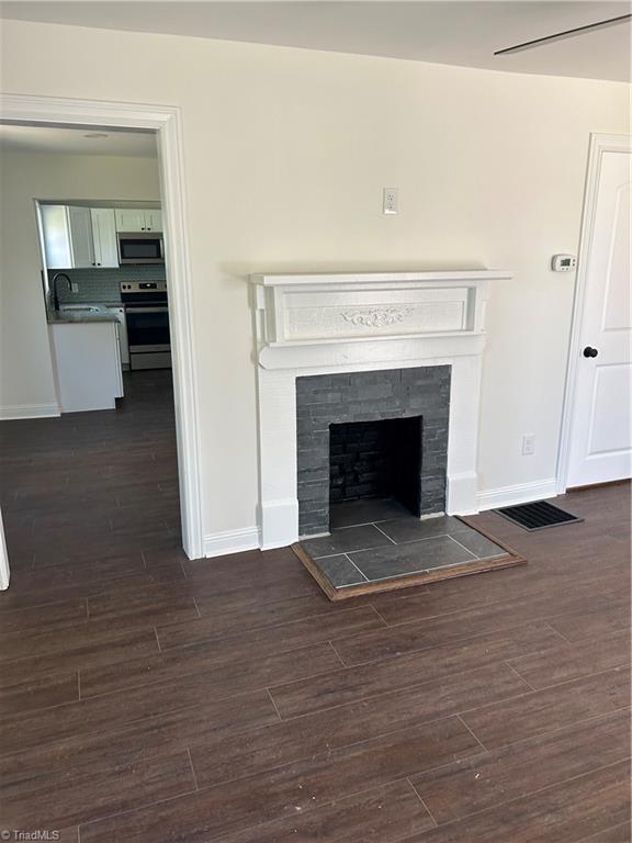 219 Highland Ave, Elkin, NC 28621 - detailed view of stainless steel appliances, baseboards, a sink, wood finished floors, and a tiled fireplace