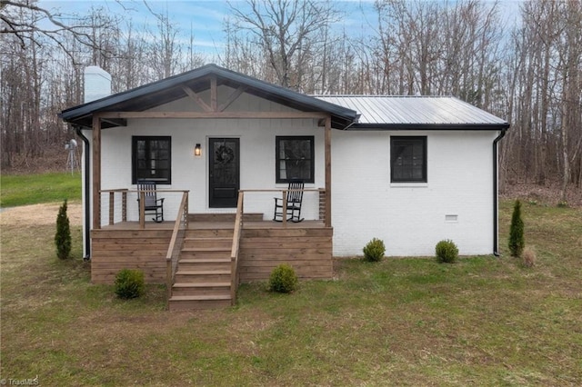 view of front of house with a front lawn, metal roof, brick siding, and a chimney