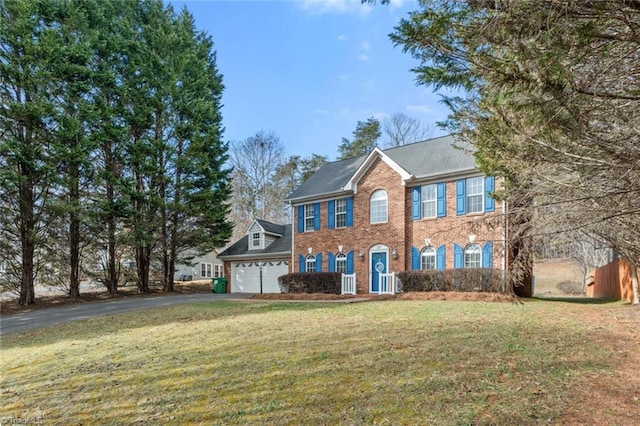 colonial house with brick siding, driveway, an attached garage, and a front lawn