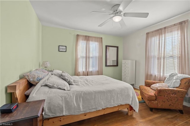 bedroom featuring multiple windows, ceiling fan, and wood finished floors