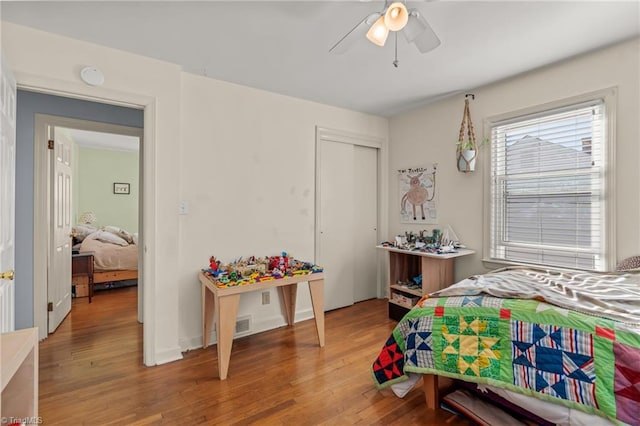 bedroom featuring light wood-style flooring, ceiling fan, and a closet