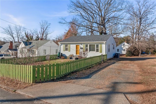 bungalow with roof with shingles, a front lawn, a fenced front yard, and cooling unit