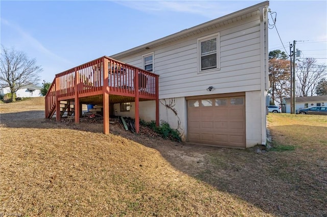 back of house featuring an attached garage, stairs, driveway, a lawn, and a wooden deck