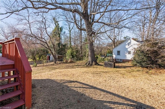 view of yard featuring fence, a deck, and stairs