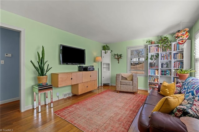 living room with baseboards, wood finished floors, visible vents, and a healthy amount of sunlight