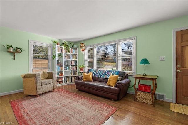 sitting room with wood-type flooring, visible vents, and baseboards