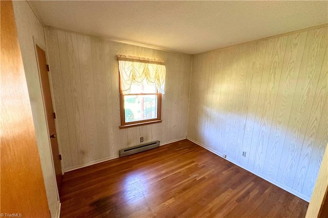 spare room featuring a baseboard radiator, dark wood-type flooring, and wooden walls