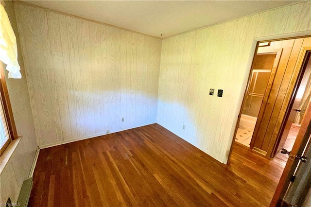 spare room with dark hardwood / wood-style flooring and wooden walls