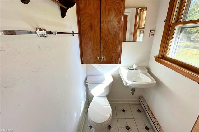 bathroom featuring toilet, a wealth of natural light, tile patterned flooring, and a baseboard heating unit