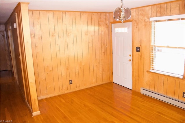 entrance foyer with hardwood / wood-style floors, a baseboard heating unit, an inviting chandelier, and wood walls