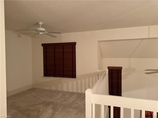 interior space featuring a textured ceiling, vaulted ceiling, carpet floors, and ceiling fan