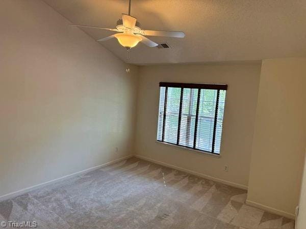 empty room featuring vaulted ceiling, carpet, and ceiling fan