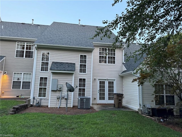 back of property featuring central air condition unit and a lawn