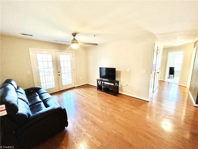 living area with visible vents, french doors, baseboards, and wood finished floors