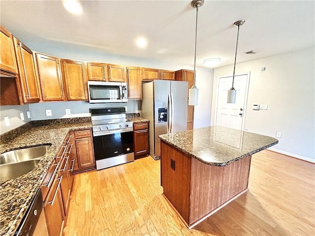 kitchen with visible vents, brown cabinets, light wood-style flooring, a kitchen island, and appliances with stainless steel finishes