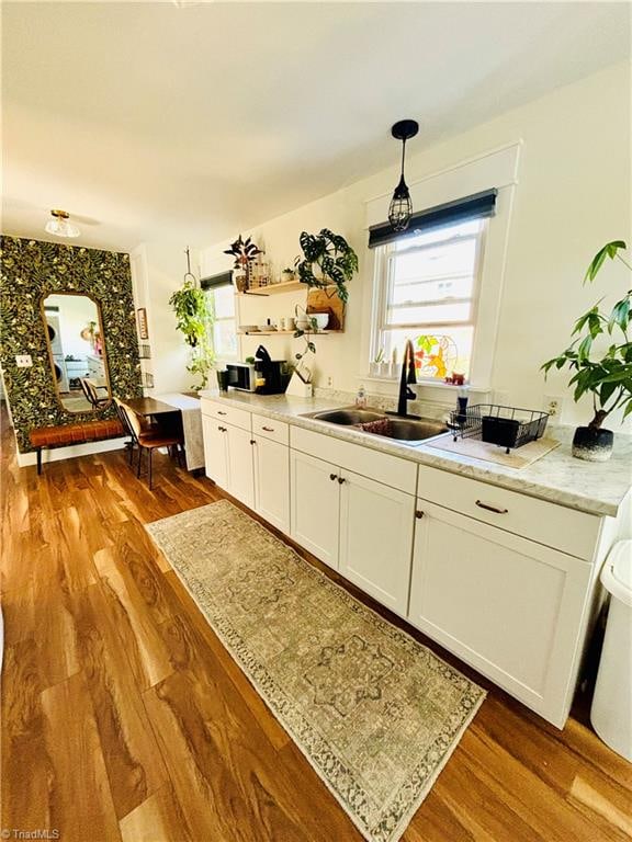 bar with sink, white cabinets, wood-type flooring, and decorative light fixtures