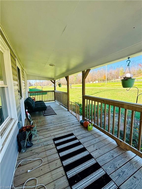 wooden terrace featuring a porch and a lawn