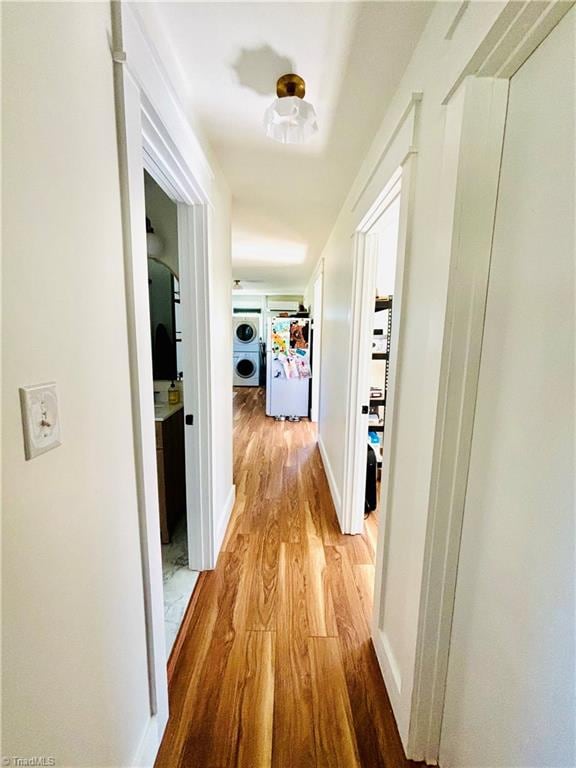 corridor with light hardwood / wood-style floors and washer / dryer