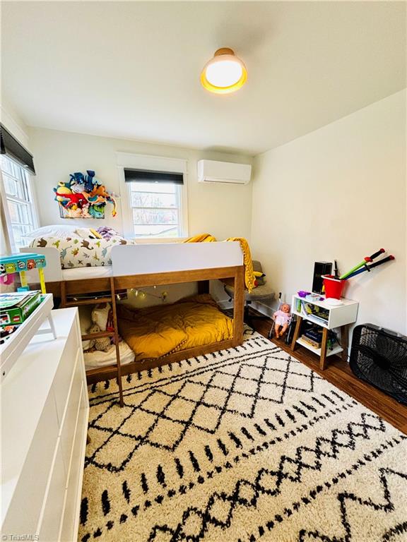 bedroom featuring hardwood / wood-style floors and a wall mounted air conditioner