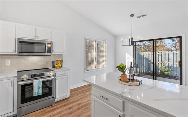 kitchen featuring stainless steel appliances, visible vents, white cabinets, vaulted ceiling, and decorative backsplash