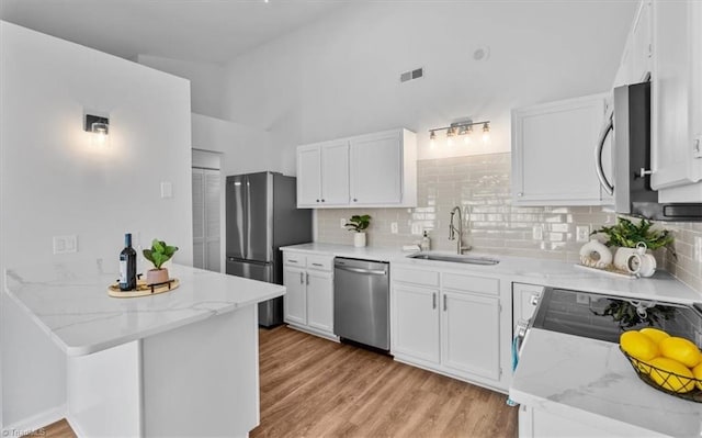 kitchen featuring light wood finished floors, visible vents, appliances with stainless steel finishes, white cabinetry, and a sink