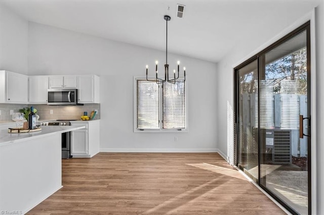 kitchen featuring stainless steel appliances, white cabinetry, light wood-style floors, light countertops, and an inviting chandelier