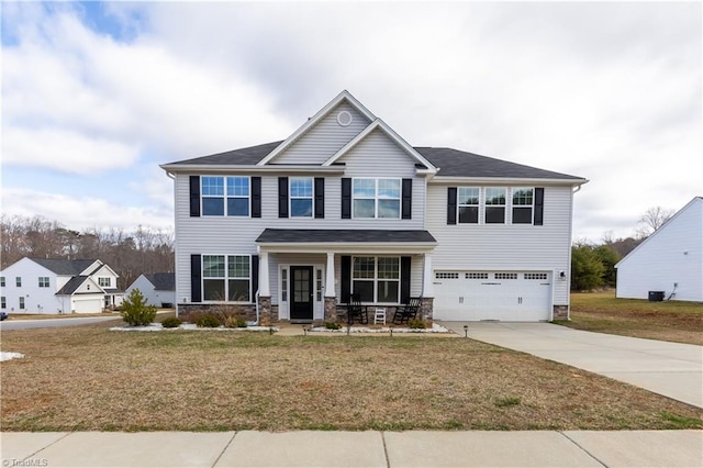 craftsman inspired home featuring a porch, an attached garage, driveway, stone siding, and a front lawn