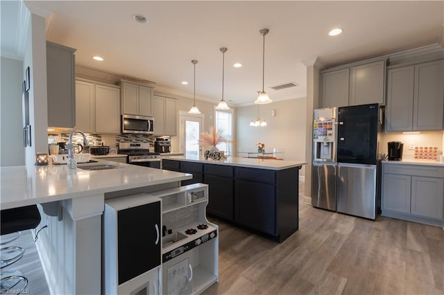 kitchen featuring appliances with stainless steel finishes, a sink, a peninsula, and gray cabinetry