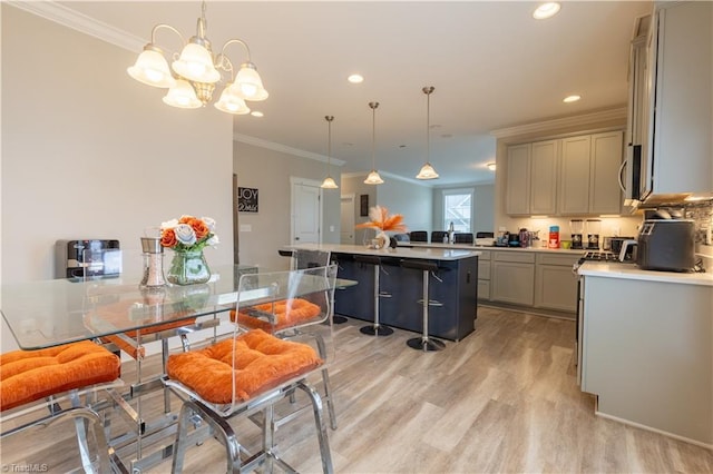 kitchen featuring ornamental molding, a kitchen breakfast bar, light wood-style floors, and gray cabinetry