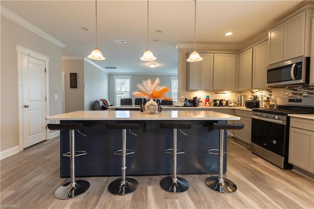 kitchen featuring appliances with stainless steel finishes, light countertops, ornamental molding, and light wood finished floors