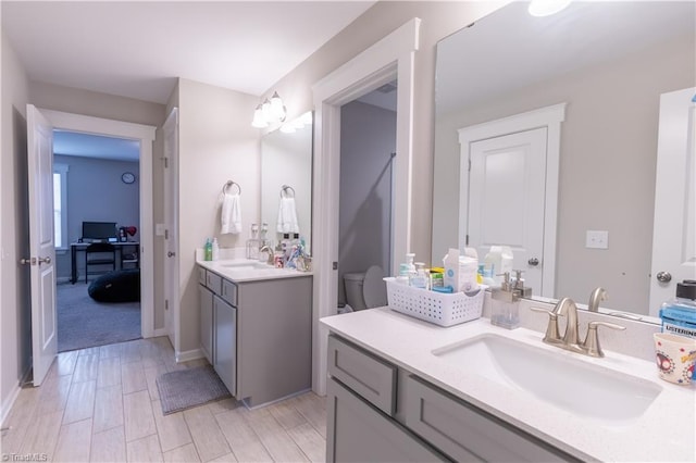 full bath featuring two vanities, a sink, and wood finish floors