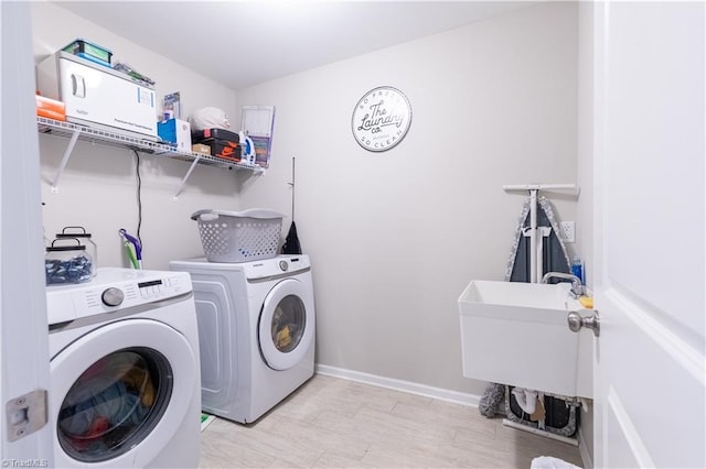 clothes washing area with washing machine and dryer, laundry area, and baseboards