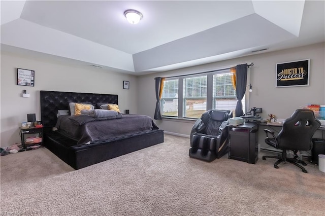 carpeted bedroom featuring a tray ceiling, visible vents, and baseboards